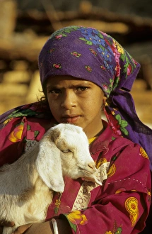 Egypt - a Bedouin girl cuddles a goat; a small Egypt - a Bedouin girl cuddles a goat; a small
