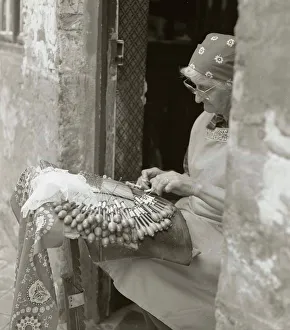 Elderly woman making lace in an open doorway Elderly woman making lace in an open doorway