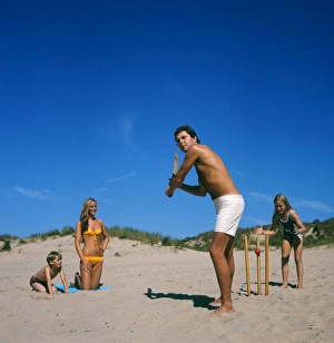 Family playing cricket on the beach, Cornwall Family playing cricket on the beach, Cornwall