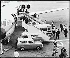 Prints of Passengers alighting from a British United Airways (BUA) plane at London Gatwick Airport, England and it is refuelled at the same time Heathrow Airport Prints: Gatwick Airport Passengers Alighting from BUA Plane Print