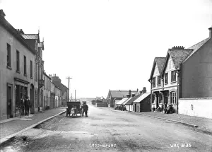 Prints of Groomsport - a view of the Main street with a motor car and children around it. There are a range of interesting buildings both sides of the street and a shop front Down Prints: Early 20th Century Groomsport Print