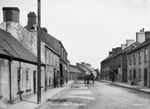 Prints of Main Street, Comber - a street scene with shop front and horse vehicle in the middle of the road. There are children to the left. (Location: Northern Ireland: County Down: Comber) Down Prints: Comber Main Street Print - Early 1900s Street Scene