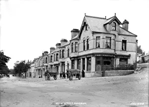 Prints of Main Street, Dundrum - a street scene with a pub at the corner and horse vehicles and people. (Location: Northern Ireland: County Down: Dundrum). Date: circa early 1900s Down Prints: Early 20th Century Dundrum Main Street Print