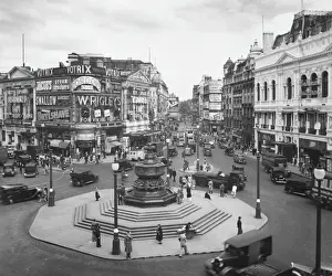 Prints of Piccadilly Circus and the Statue of Eros, London. The street scene is dominated by advertising hoardings and illuminations for Gordons Gin, Wrigleys Chewing Gum and others Famous Statue Prints: Piccadilly Circus and the Statue of Eros, London Print 1930s