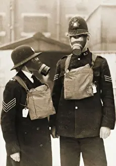 Prints of A policeman and a policewoman wearing civilian gas masks outside Harrow Road Police Station (X Division) before the outbreak of World War Two. The respirator is contained in the canvas bag Police Prints: Policeman and Policewoman with Gas Masks Print, London 1939