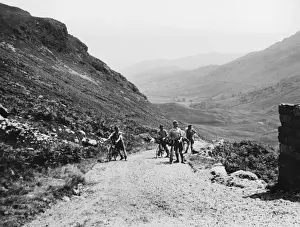 Prints of Touring cyclists, ramblers, pausing for a breather while climbing the steep and rugged Wrynose Pass, one of the wildest parts of Langdale Valley, Westmorland, England Westmorland Prints: Wrynose Pass Print