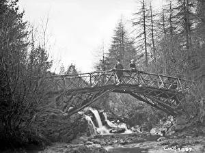 Prints of a view of a rustic wooden bridge over a river and two men on it (unsharp), taken in Apr. 1908. (Location: Northern Ireland; County Antrim; Glenariff). Date: circa early 1900s River Prints: Rustic Wooden Bridge Print, Glenariff, Northern Ireland
