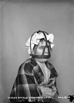 Prints of Scolds Bridle from Armagh Jail - a view of a woman sitting with the bridle over her face, to stop her talking. (Location: Ireland). Date: circa early 1900s Armagh Prints: Scolds Bridle Print - Armagh Jail, Ireland, circa early 1900s