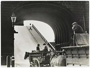 Prints of Two horse-drawn carts, one from the Metropolitan Cartage Co. wait while Londons Tower Bridge opens Tower Bridge Prints: Tower Bridge Print: Two Horse-Drawn Carts Waiting to Cross