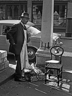 Tradesman repairs chairs in Central London street Tradesman repairs chairs in Central London street