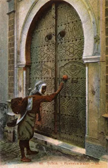 Tunis - Tunisia, water carrier knocking on ornate door Tunis - Tunisia, water carrier knocking on ornate door