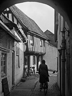 Woman cycling along path between houses Woman cycling along path between houses