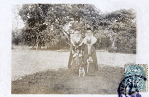 Two women and two children in a garden, with a dog Two women and two children in a garden, with a dog