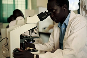 Prints of Blood analysis. Doctor using a light microscope to analyse a sample of blood. Blood disorders that can be diagnosed this way include malaria. Photographed the Gulu region of Uganda Images Dated 2007 March: Blood Analysis Print: Doctor Examining Blood Sample Under Microscope