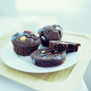 Prints of Chocolate cakes on a plate. Cakes are baked from a mixture of flour, fat, sugar and eggs. Chocolate comes from the cocoa plant and contains added fats and sugars Images Dated 2003 June: Chocolate Cakes Print on Plate