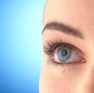 Close-up of a womans blue eye with a tear-drop Close-up of a womans blue eye with a tear-drop