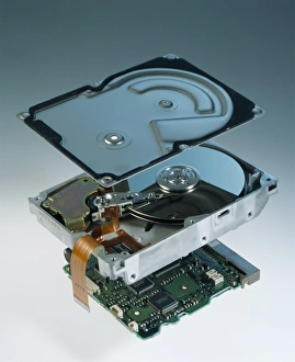 Prints of Computer hard disk assembly. Component parts of a hard disk showing the outer aluminium casing (top), the hard disk platter and read/write head (centre), and the controller electronics (bottom) Images Dated 2003 July: Hard Disk Assembly Print