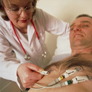 Doctor puts electrodes on mans chest for ECG test Doctor puts electrodes on mans chest for ECG test