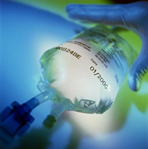 Gloved hand reaches for an intravenous drip bag Gloved hand reaches for an intravenous drip bag