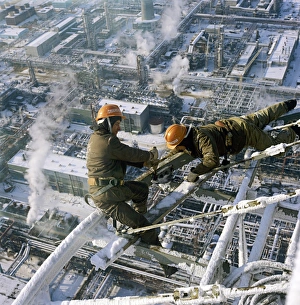 Prints of High-rise construction work. Workers building a high-rise industrial structure. The Astrakhan gas refinery is seen in the background. The refinery is in Astrakhan, in the Volga region of Russia Images Dated 2007 August: High-Rise Construction Print