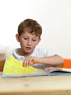 Prints of MODEL RELEASED. Learning to read. 6 year old boy learning to read Images Dated 2011 February: Learning to Read Print: 6-Year-Old Boy in Reading Position