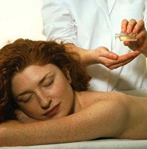 Masseuse pours oil before massaging a woman Masseuse pours oil before massaging a woman