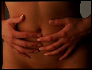 Menstrual pain: womans hands holding her abdomen Menstrual pain: womans hands holding her abdomen
