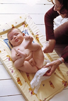 Prints of MODEL RELEASED. Nappy change. Mother changing her six-month-old baby boys disposable nappy Images Dated 2003 March: Disposable Nappy Change Print