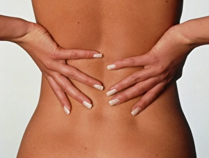 Back pain: womans hands held to her lower back Back pain: womans hands held to her lower back