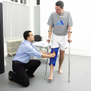 Prints of MODEL RELEASED. Physiotherapy. Physiotherapist assessing the mobility in a patients knee. The patient is wearing a brace to immobilise his leg after an injury Images Dated 2006 January: Physiotherapy Print: Patient with Knee Brace