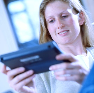 A woman reads on a portable electronic book, its screen displaying text