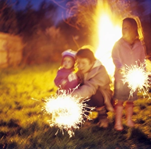 Prints of MODEL RELEASED. Sparklers. Mother supervises her children using sparklers. Children using fireworks should be supervised by adults at all times Images Dated 2005 September: Sparklers Model Released Print