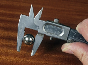 Prints of Using Vernier calipers. This measuring device is being used to measure the diameter of a metal ball bearing. The external jaws are being used Images Dated 2006 February: Using Vernier Calipers to Measure a Metal Ball Bearing Print