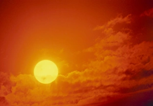 View of the Sun setting in a cloudy sky View of the Sun setting in a cloudy sky