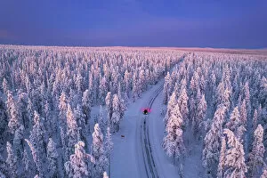 Finland Collection: Aerial view of a car driving through the winter forest covered from snow at dawn, Akaslompolo