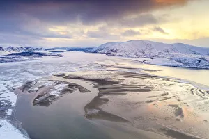 Aerial view of cold sea framed by snow capped mountains at sunset Aerial view of cold sea framed by snow capped mountains at sunset
