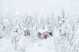 Finland Collection: Aerial view of happy couple enjoying the winter holidays in a frozen hut in the snowy forest