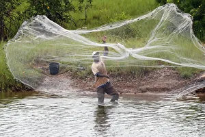 African fisherman throwing net into the river in traditional way, Aneho, Togo African fisherman throwing net into the river in traditional way, Aneho, Togo