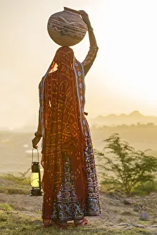Ahir Woman in traditional colorful cloth carrying water in a clay jug on her head Ahir Woman in traditional colorful cloth carrying water in a clay jug on her head