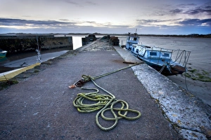 Beadnell Harbour at dusk showing old rope coiled on harbourside and dilapidated fishing boat Beadnell Harbour at dusk showing old rope coiled on harbourside and dilapidated fishing boat