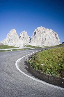 A bend in a road passing the craggy peaks of the Sassolungo in the Dolomites A bend in a road passing the craggy peaks of the Sassolungo in the Dolomites