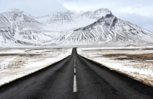 Black tarmac road leading towards snow covered mountains in winter, South Iceland Black tarmac road leading towards snow covered mountains in winter, South Iceland