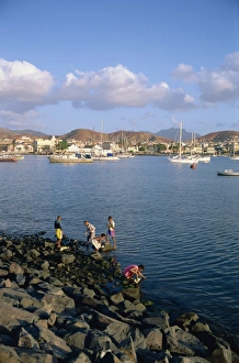 Boys on the rocks, with the harbour and town in the background, at Mindelo Boys on the rocks, with the harbour and town in the background, at Mindelo