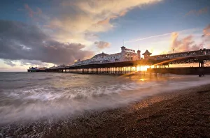 Brighton Pier at sunset with dramatic sky and waves washing up the beach, Brighton Brighton Pier at sunset with dramatic sky and waves washing up the beach, Brighton