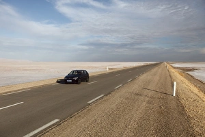Chott El Jerid, a flat dry salt lake, and automobile on highway between Tozeur and Kebili Chott El Jerid, a flat dry salt lake, and automobile on highway between Tozeur and Kebili