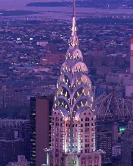 The top of the Chrysler Building illuminated in the evening with a bridge The top of the Chrysler Building illuminated in the evening with a bridge