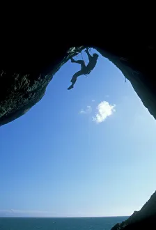 A climber ascending a cave archway at Foxhole, Gower Peninsula, Wales, United Kingdom A climber ascending a cave archway at Foxhole, Gower Peninsula, Wales, United Kingdom