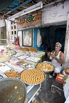 Diwali sweet stall with stallholder and picture of the Hindu god, Hanuman Diwali sweet stall with stallholder and picture of the Hindu god, Hanuman