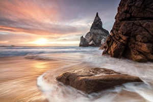Colorful Coastal Scene Prints: The fiery sky at sunset is reflected on the ocean waves and cliffs, Praia da Ursa