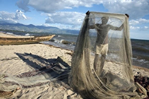 A fisherman tends his nets on Plage des Cocotiers (Coconut Beach) also known as Saga Beach A fisherman tends his nets on Plage des Cocotiers (Coconut Beach) also known as Saga Beach